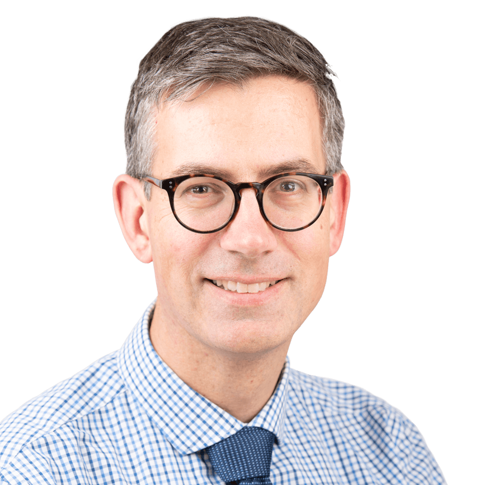 Dr Simon Wilson Vasectomy Surgeon smiling in a professional headshot wearing dark glasses and a blue checkered shirt