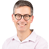 Professional headshot of Dr Simon Wilson smiling warmly against a bright white background