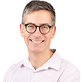 Professional headshot of Dr Simon Wilson smiling warmly against a bright white background